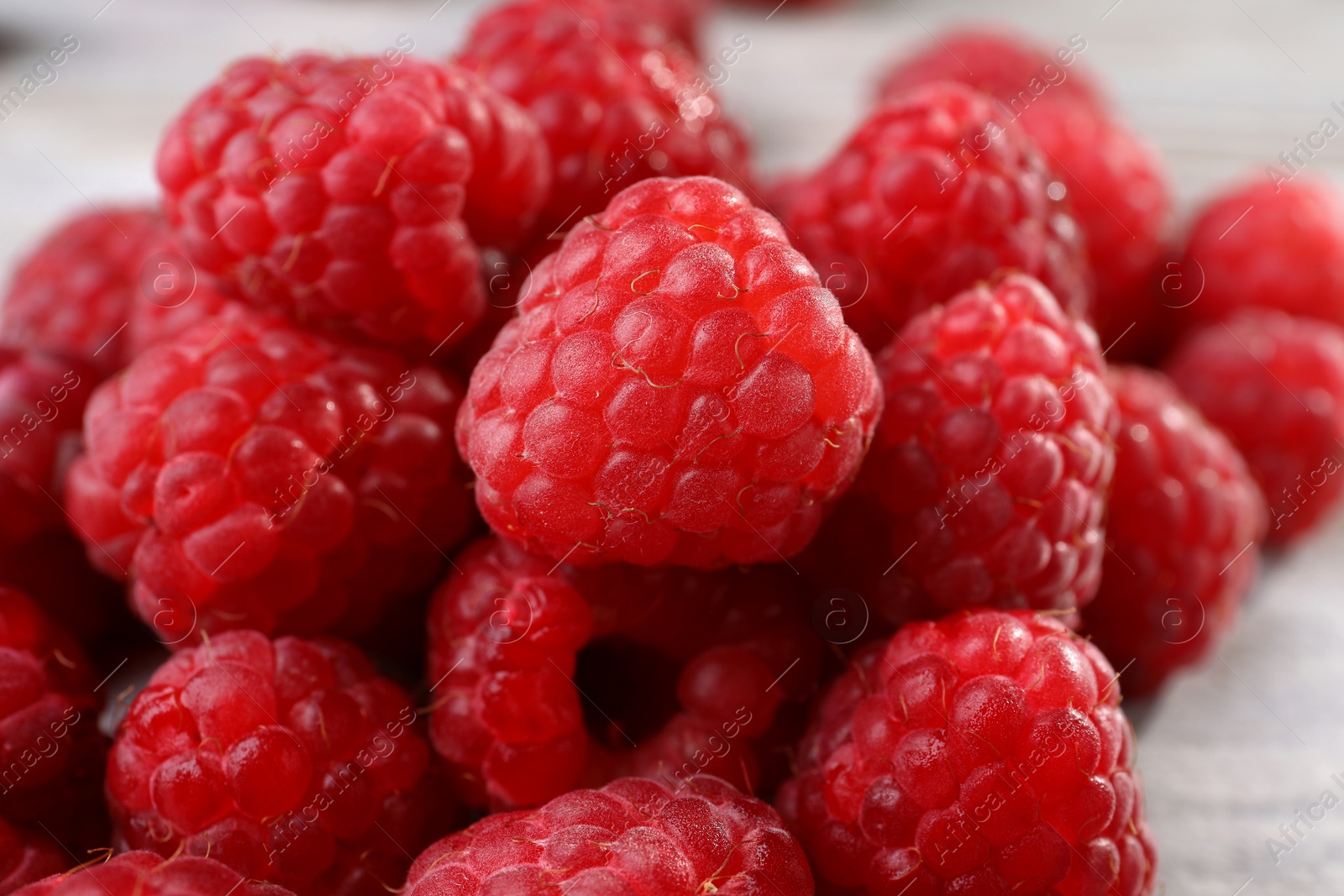 Photo of Heap of tasty ripe raspberries on table, closeup