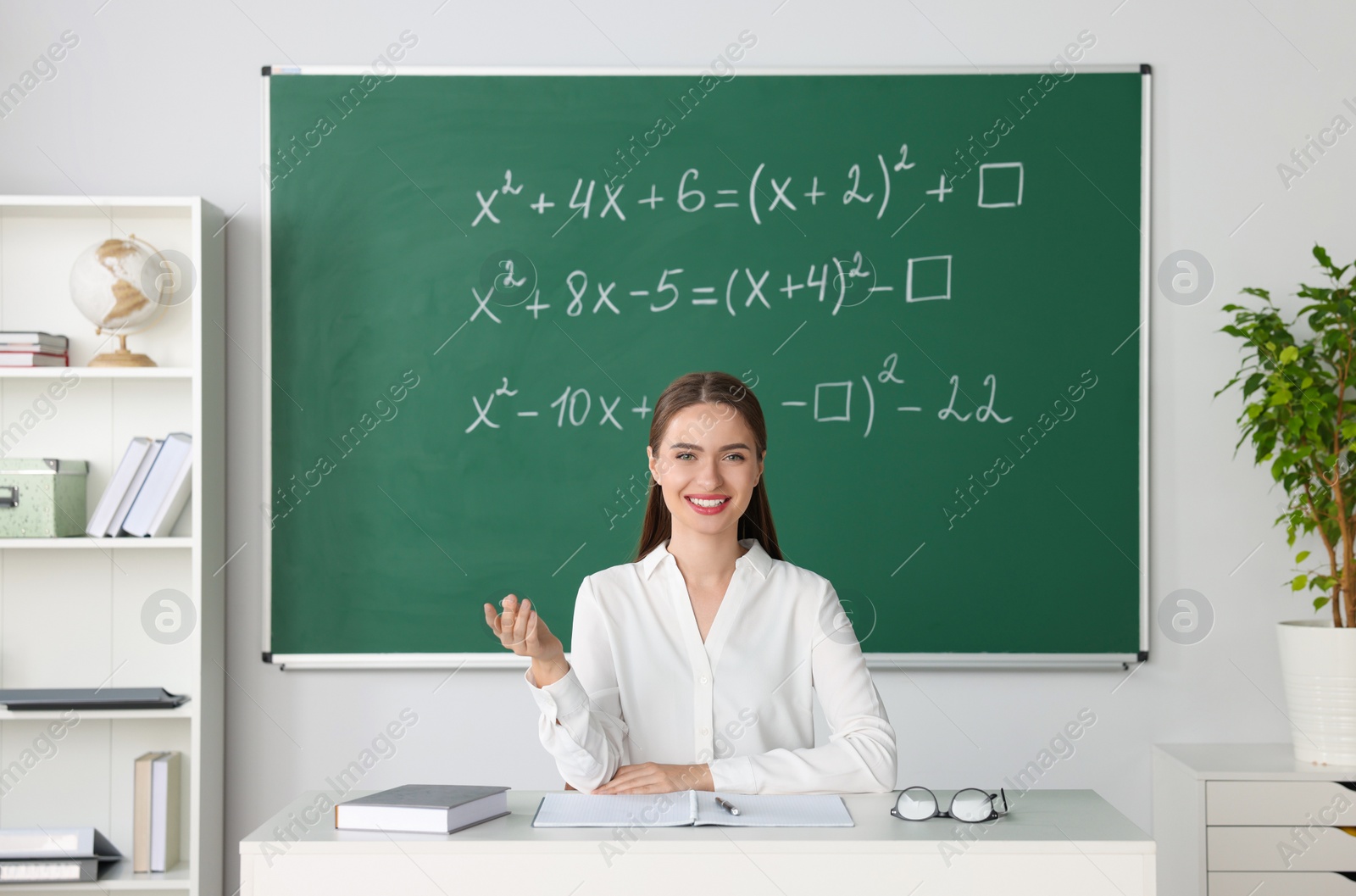 Photo of Young math’s teacher giving lesson at table in classroom