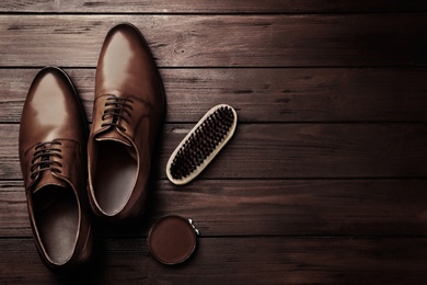 Image of Flat lay composition with shoe care accessories and footwear on wooden background. Space for text