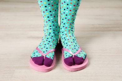 Woman wearing bright socks with flip-flops standing on floor