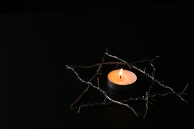 Photo of Burning candle and star of David made with barbed wire on black background. Holocaust memory day