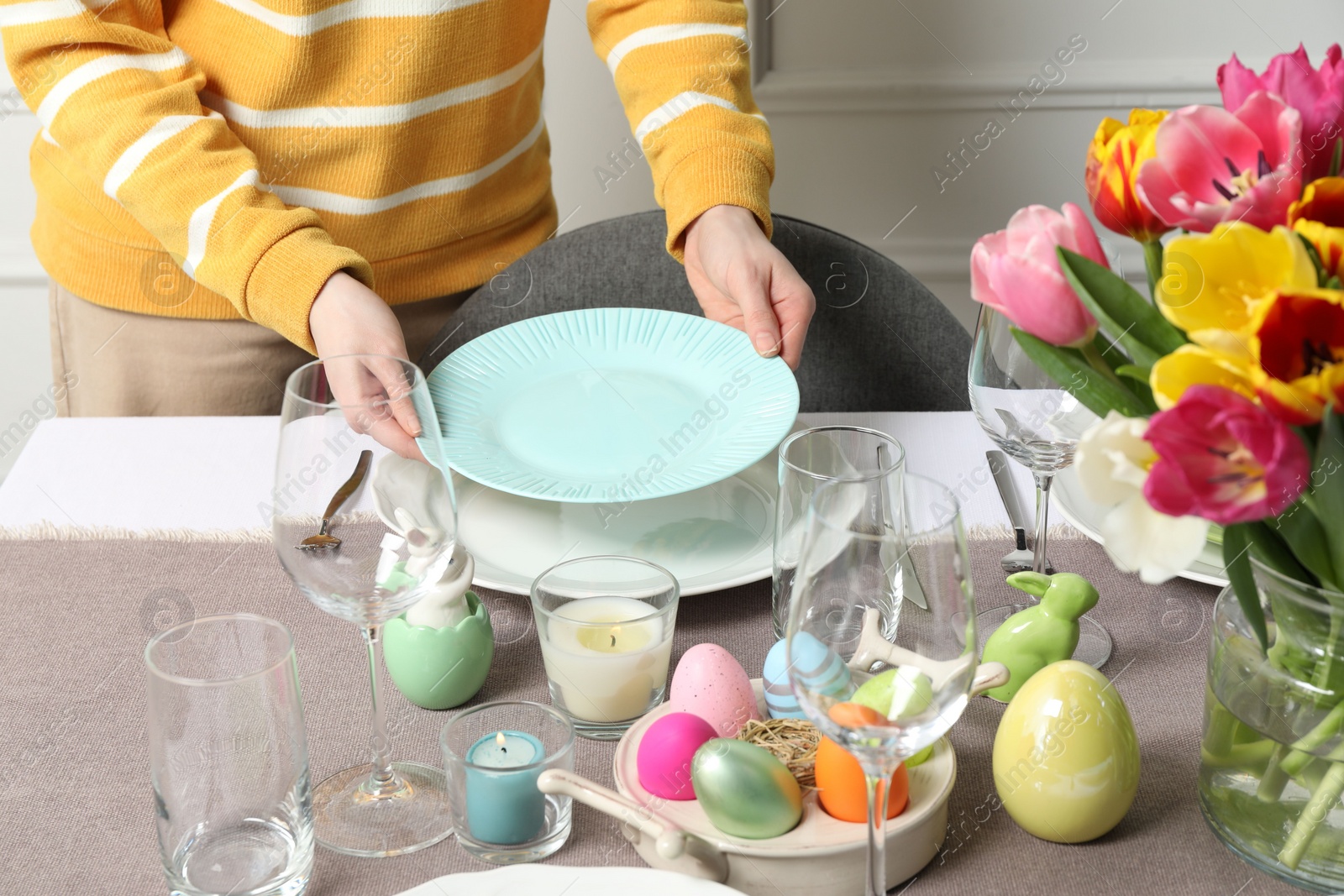 Photo of Woman setting table for festive Easter dinner at home, closeup