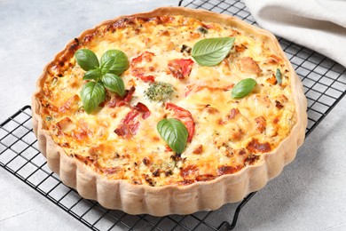 Tasty quiche with tomatoes, basil and cheese on light textured table, closeup