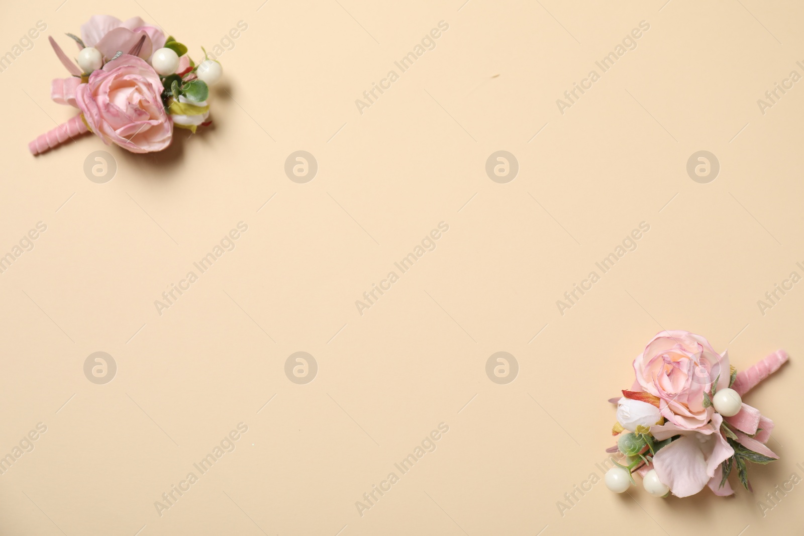 Photo of Stylish pink boutonnieres on beige background, top view. Space for text