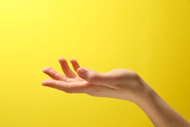 Photo of Woman holding something in hand on yellow background, closeup