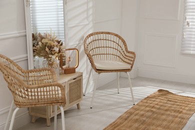 Photo of Living room interior with wooden commode, mirror and wicker chairs