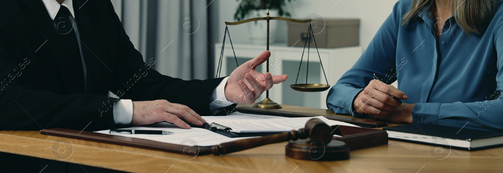 Image of Lawyer working with client at wooden table in office, closeup. Banner design