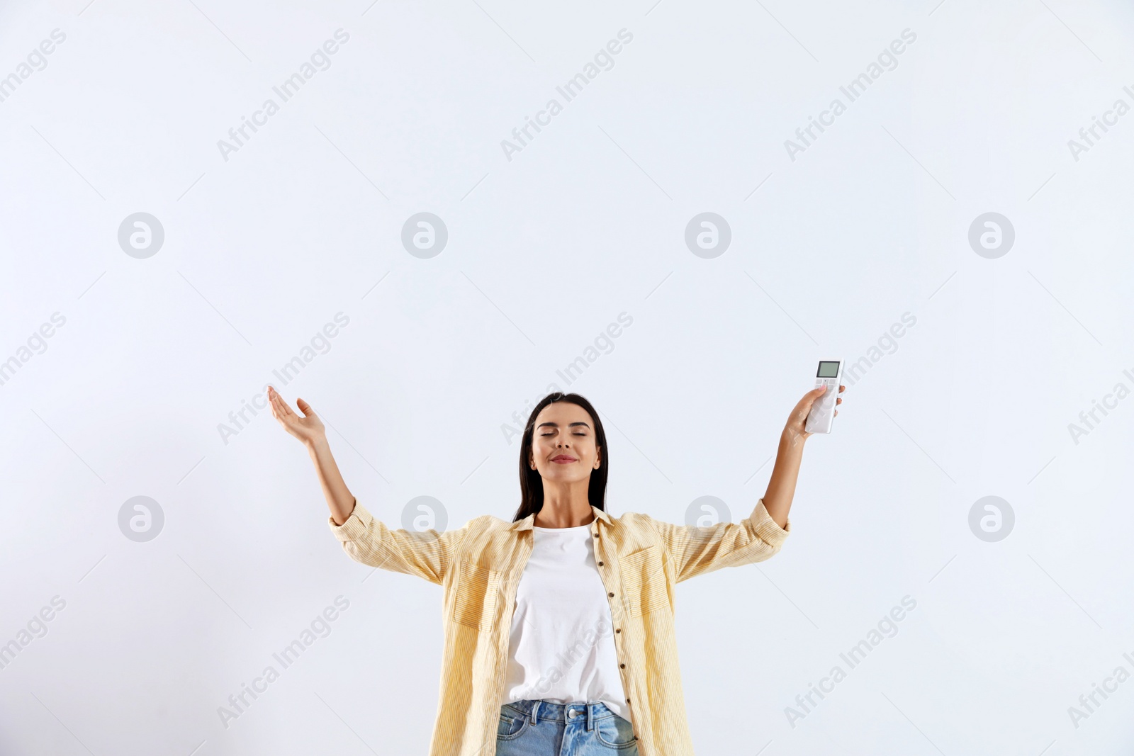 Photo of Young woman with air conditioner remote on white background