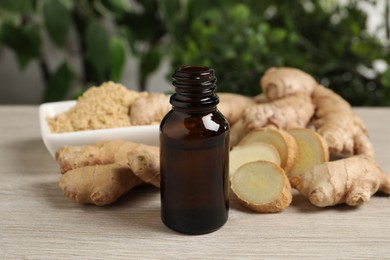 Photo of Ginger essential oil in bottle on light wooden table