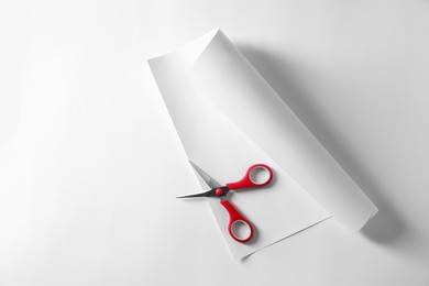 Photo of Red scissors and paper on white background, top view. Space for text