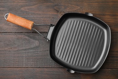 One grill frying pan on wooden table, top view with space for text. Cooking utensil