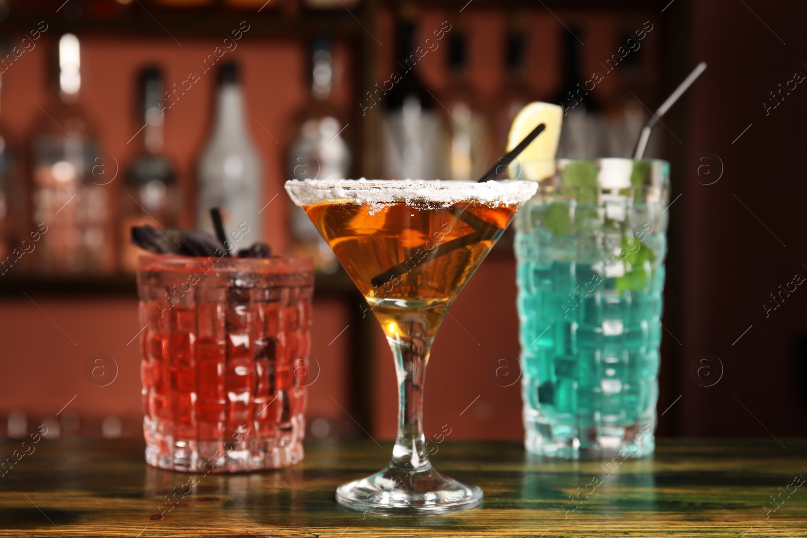 Photo of Glasses with delicious cocktails on counter in bar