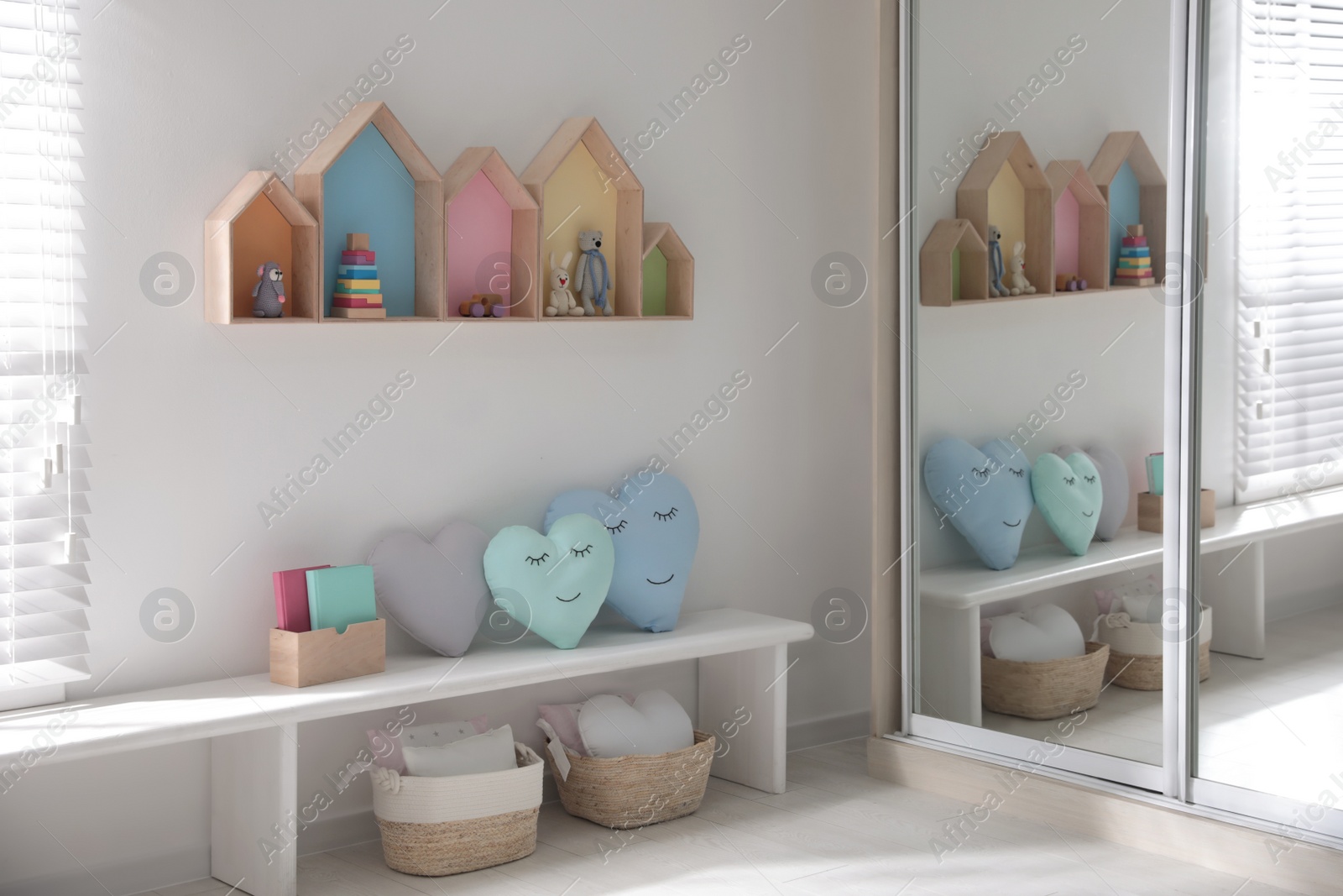 Photo of Cute children's room interior design with house shaped shelves on white wall and bench