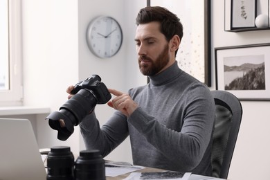 Professional photographer with digital camera at table in office