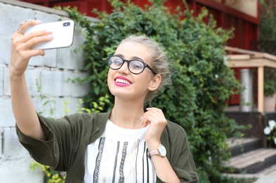 Attractive woman taking selfie on city street