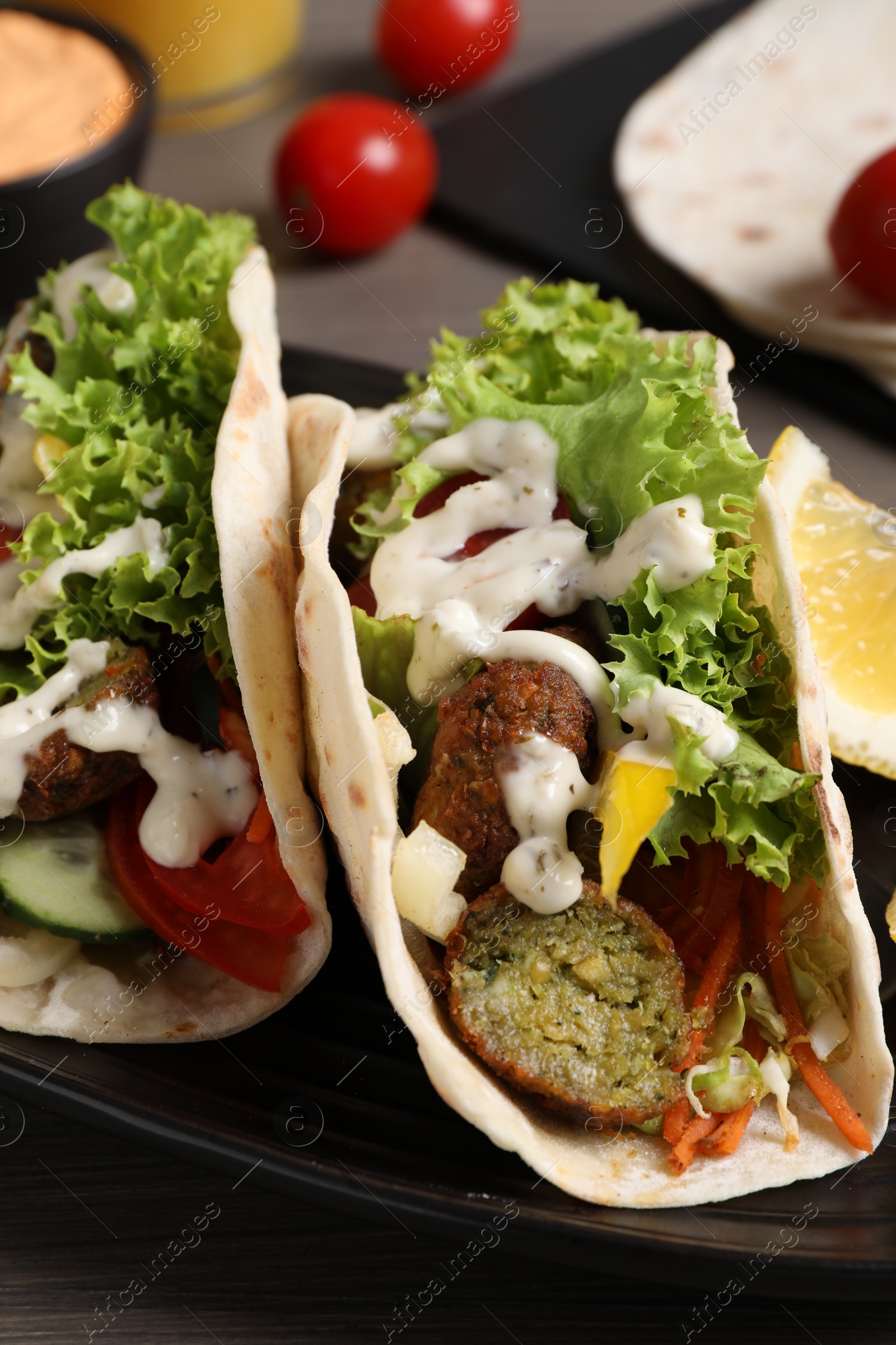 Photo of Delicious fresh vegan tacos served on wooden table, closeup