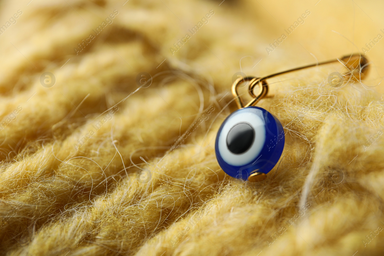 Photo of Evil eye safety pin on knitted clothing, closeup