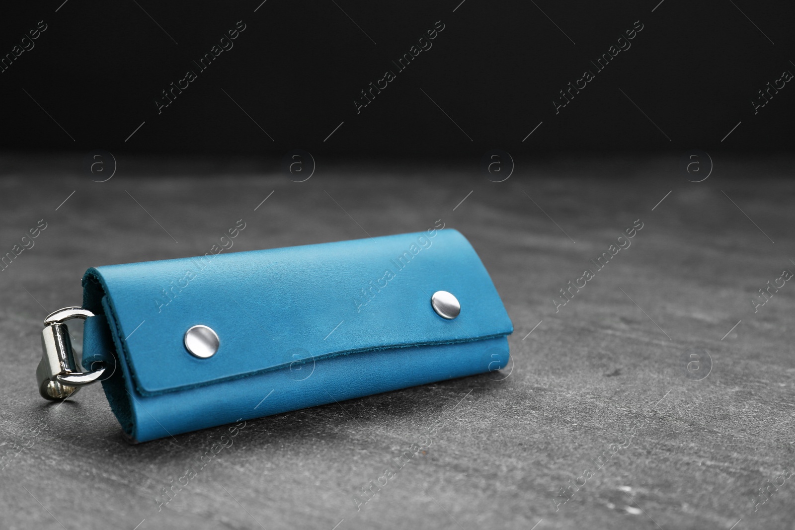 Photo of Stylish leather keys holder on grey table, closeup. Space for text
