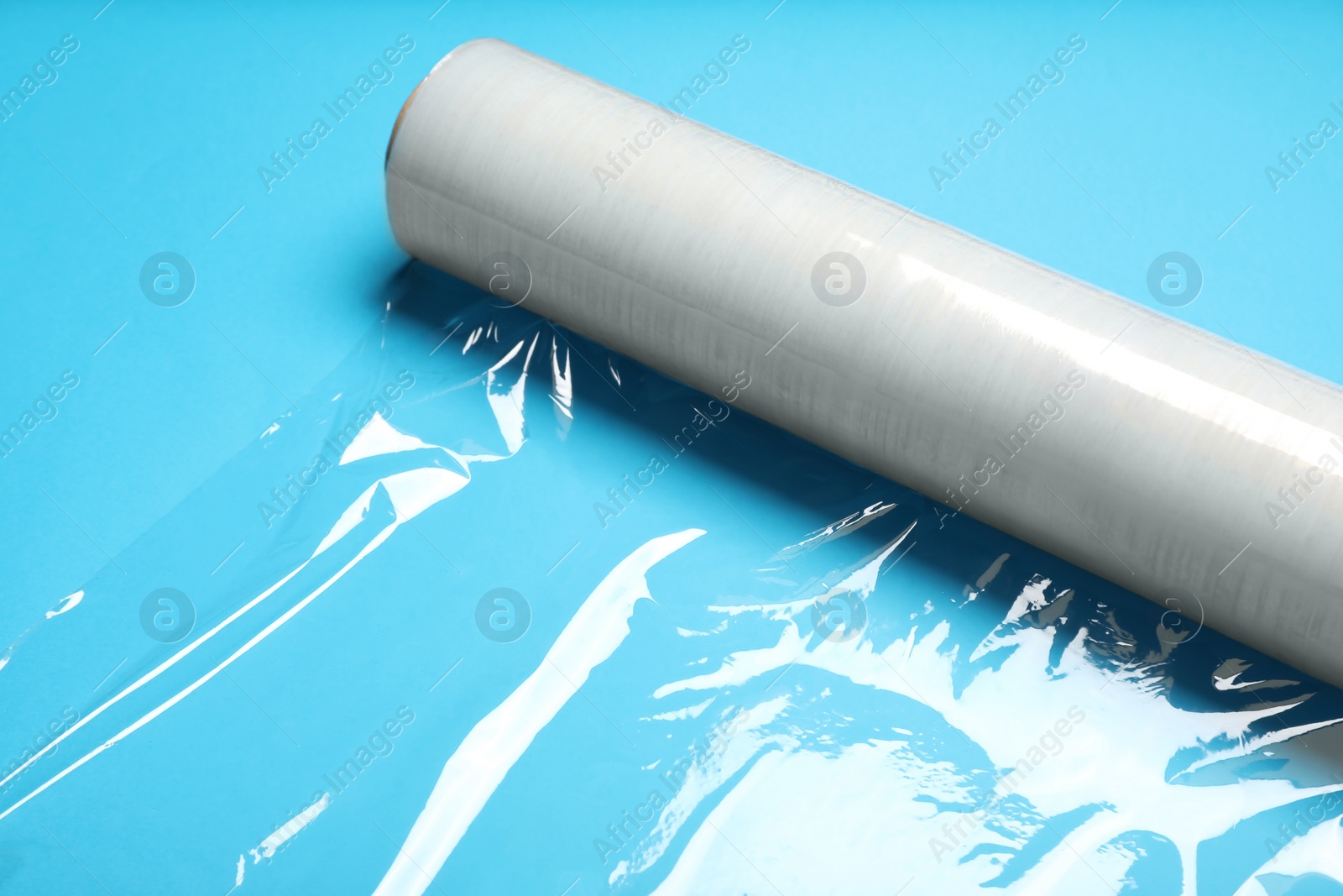 Photo of Roll of transparent stretch wrap on turquoise background, closeup