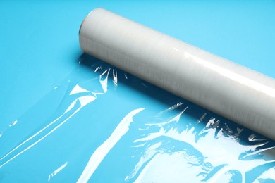 Photo of Roll of transparent stretch wrap on turquoise background, closeup