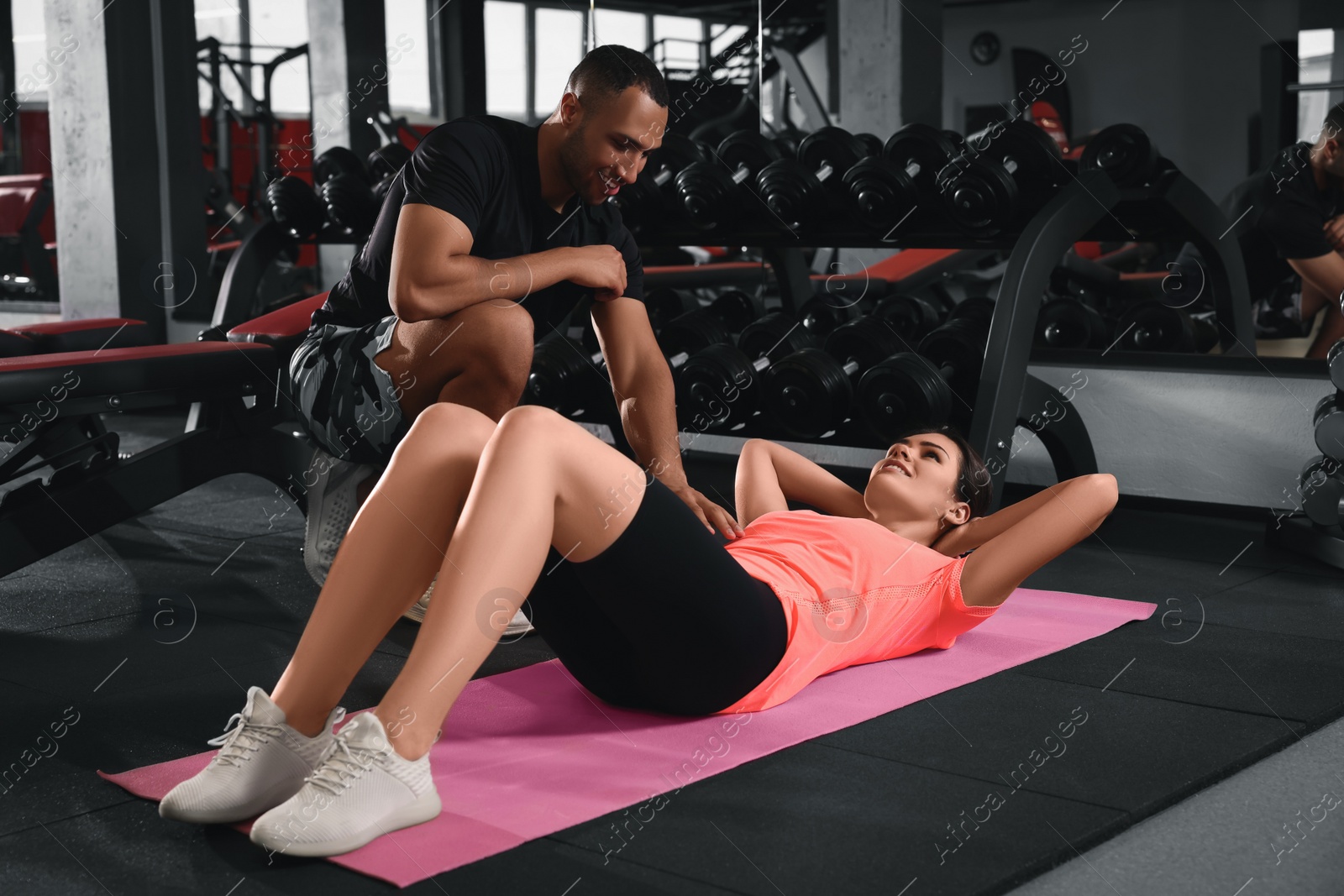 Photo of Trainer explaining woman how to do exercise properly in modern gym