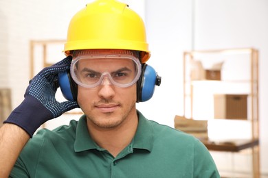 Worker wearing safety headphones indoors. Hearing protection device