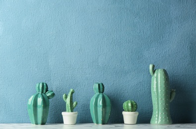 Photo of Decorative cacti on table near color wall, space for text. Interior decor