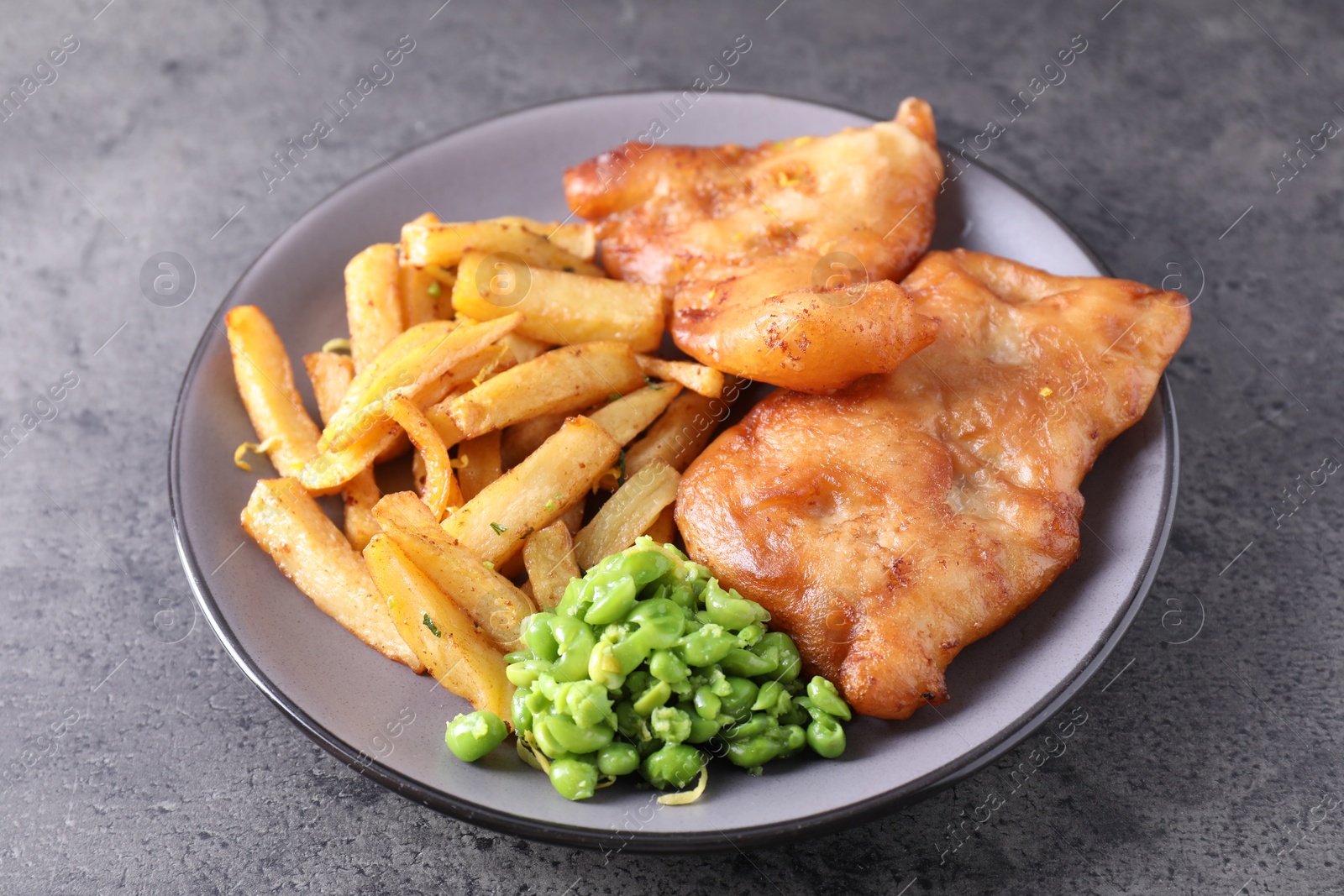 Photo of Tasty fish, chips and peas on grey table