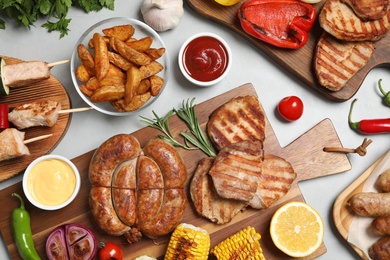 Photo of Flat lay composition with barbecued meat and vegetables on light table