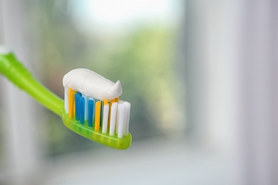 Toothbrush with paste on blurred background, closeup