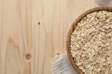 Photo of Bowl with oatmeal on wooden table, top view. Space for text