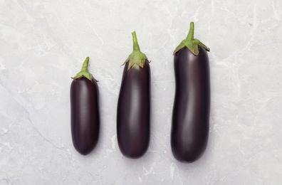 Raw ripe eggplants on grey table, flat lay