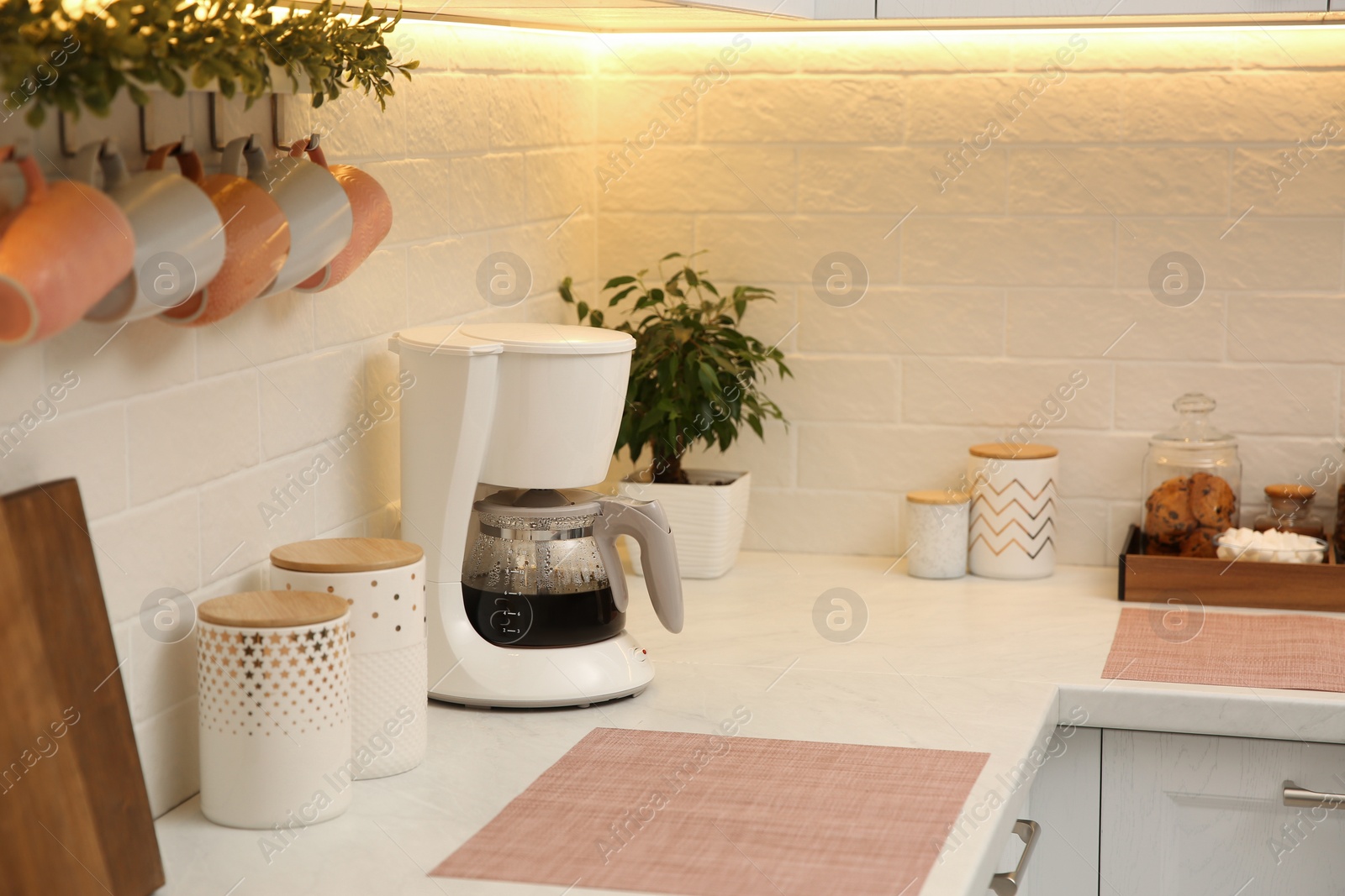 Photo of Modern coffeemaker on countertop near brick wall in kitchen
