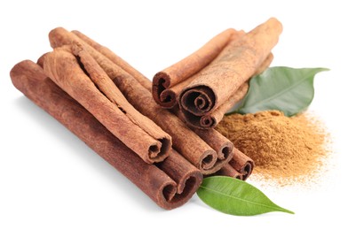 Photo of Dry aromatic cinnamon sticks, powder and green leaves isolated on white