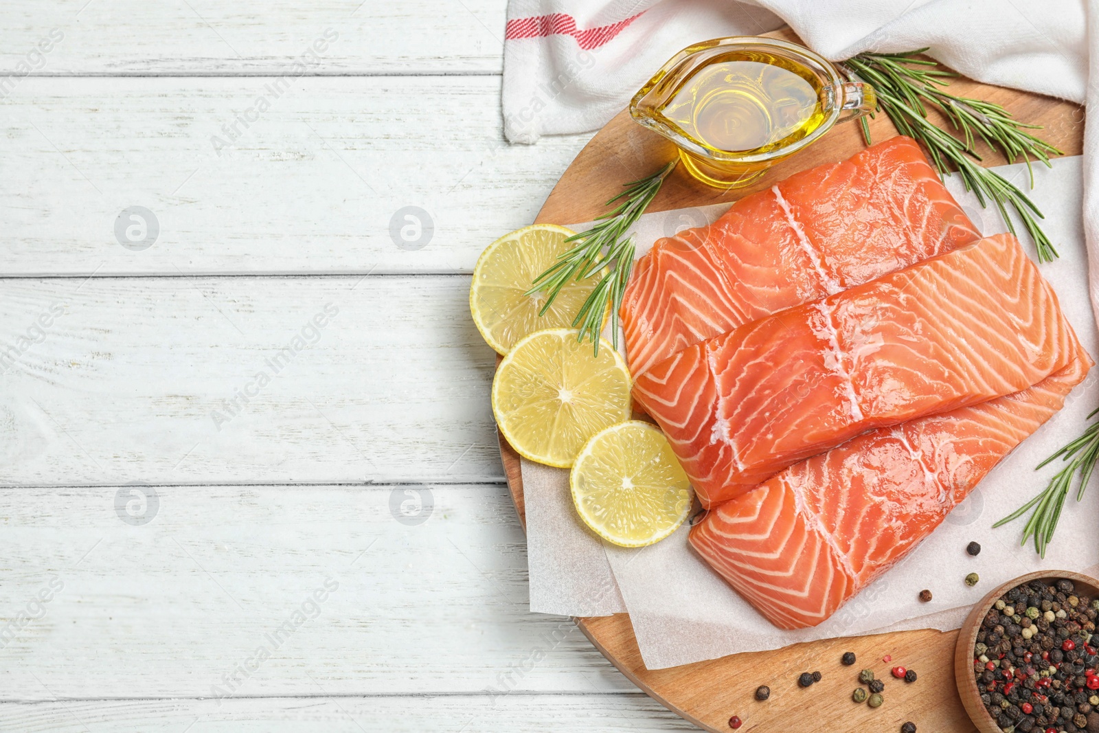 Photo of Top view of fresh raw salmon and products on white wooden table, space for text. Fish delicacy