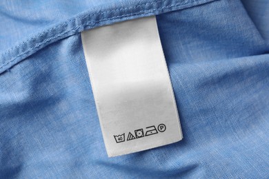 Photo of White clothing label on light blue garment, closeup