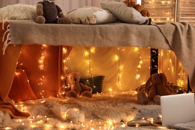 Photo of Beautiful play tent decorated with festive lights and toys at home