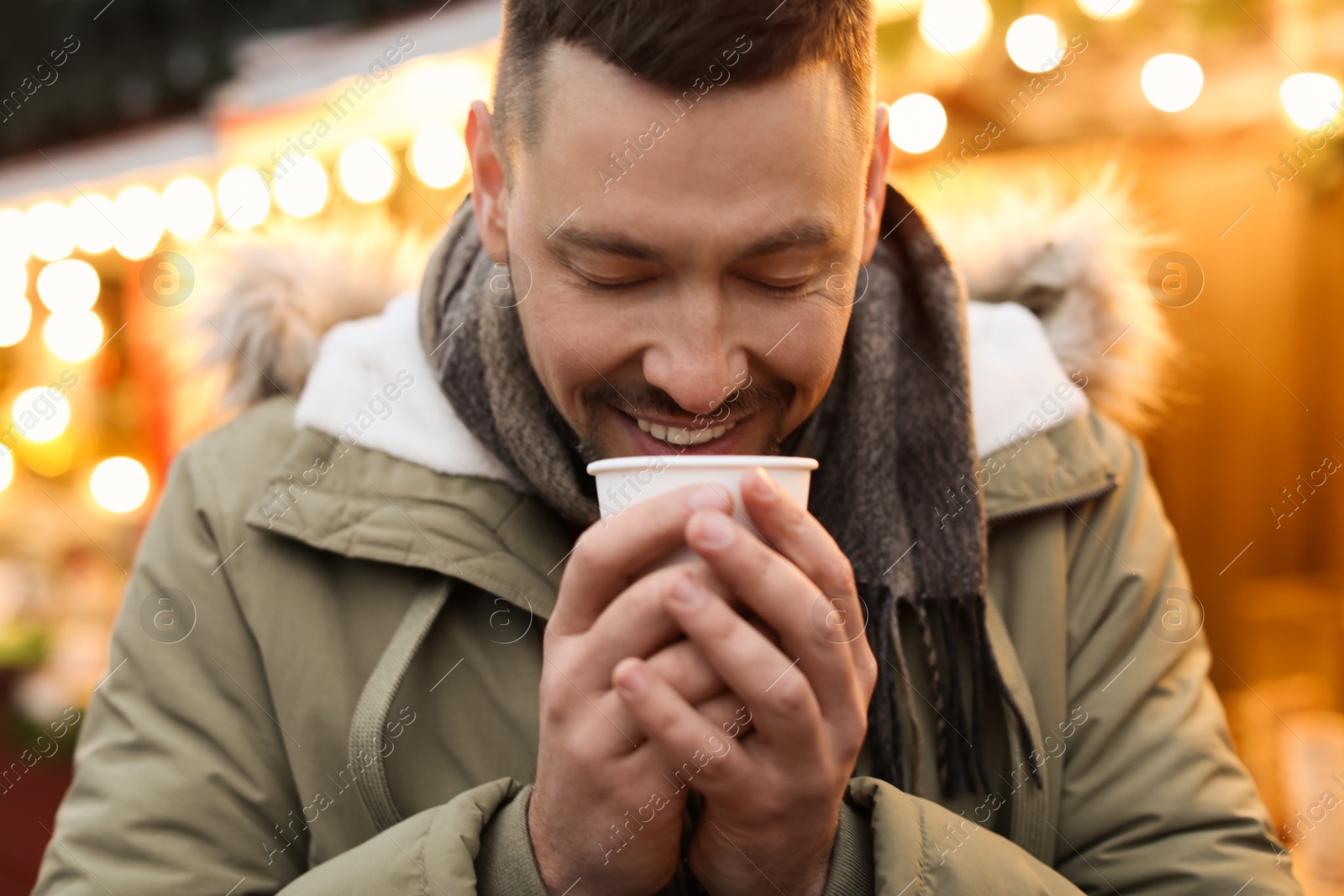 Photo of Happy man with mulled wine at winter fair