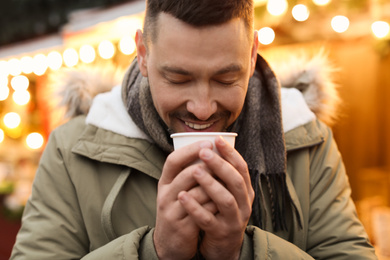 Photo of Happy man with mulled wine at winter fair