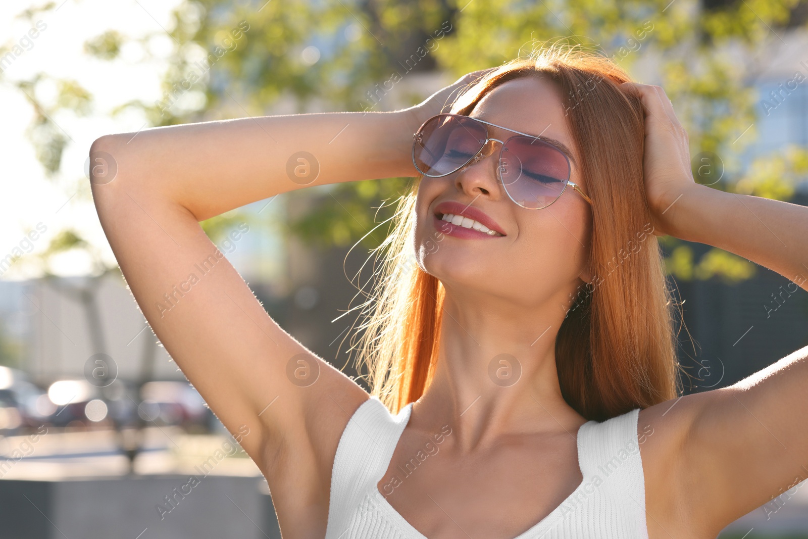 Photo of Beautiful smiling woman in sunglasses outdoors on sunny day