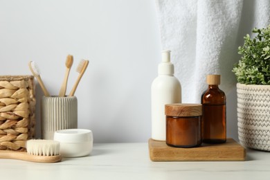 Photo of Different bath accessories and personal care products on light marble table against white wall