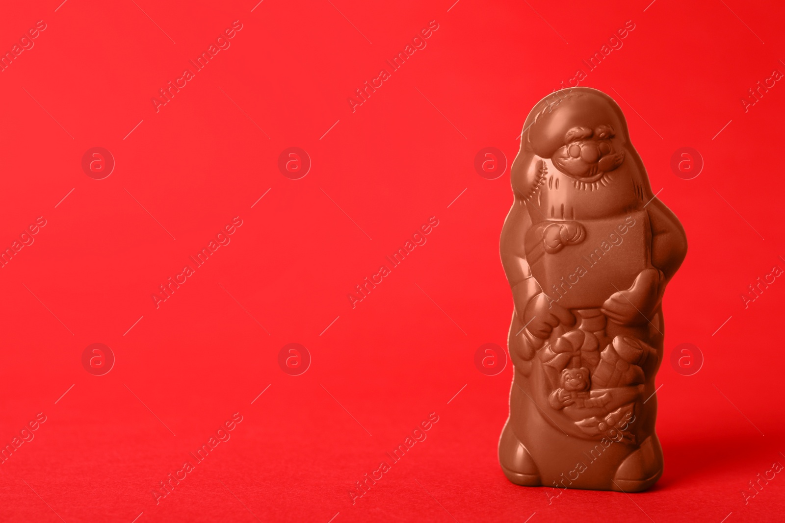 Photo of Unwrapped chocolate Santa Claus on red background. Space for text