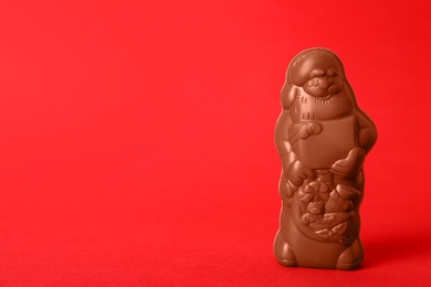 Photo of Unwrapped chocolate Santa Claus on red background. Space for text