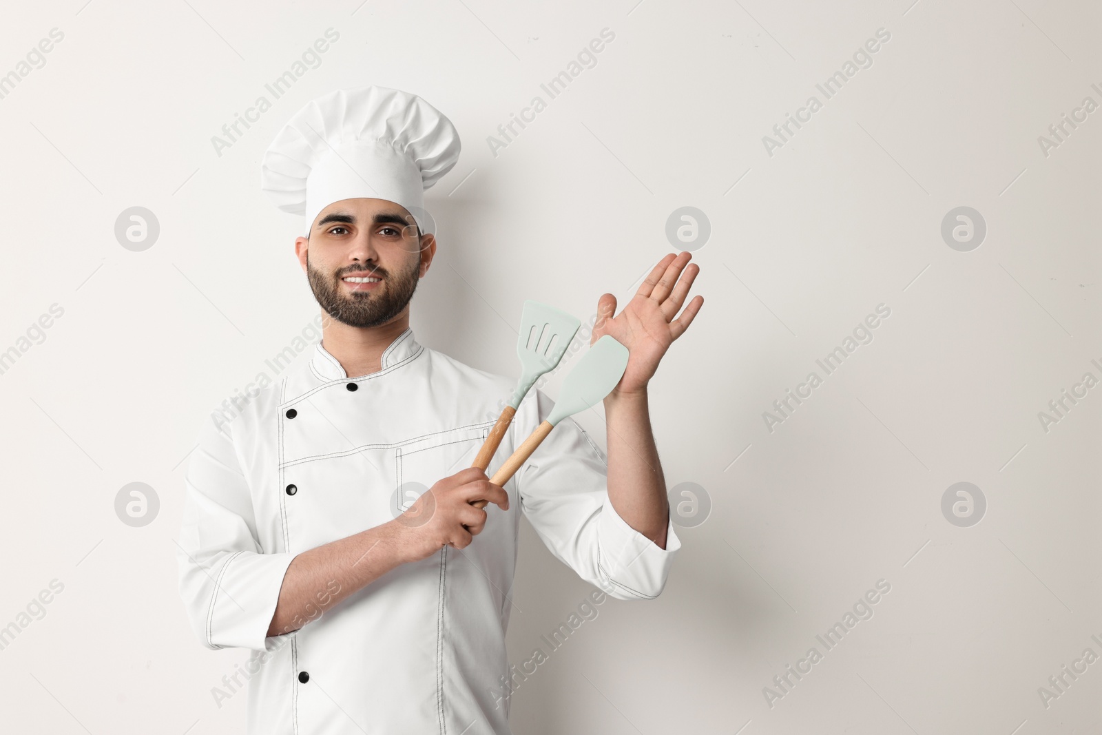 Photo of Professional chef holding kitchen utensils on white background