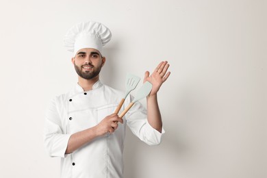 Professional chef holding kitchen utensils on white background