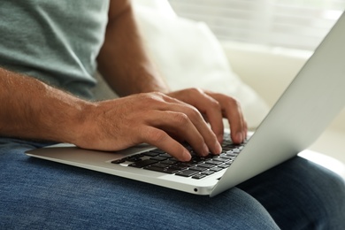 Photo of Man using laptop for search indoors, closeup