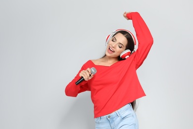 Young woman singing into microphone on color background. Christmas music
