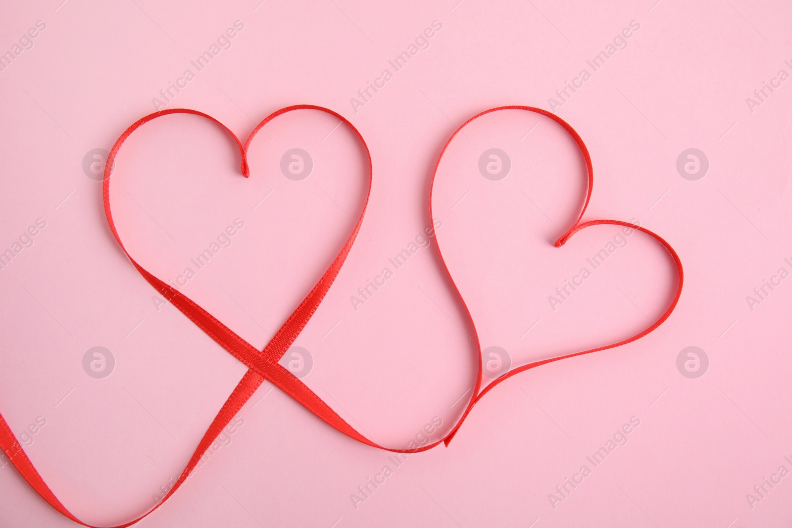Photo of Hearts made of red ribbon on pink background, top view. Valentine's day celebration