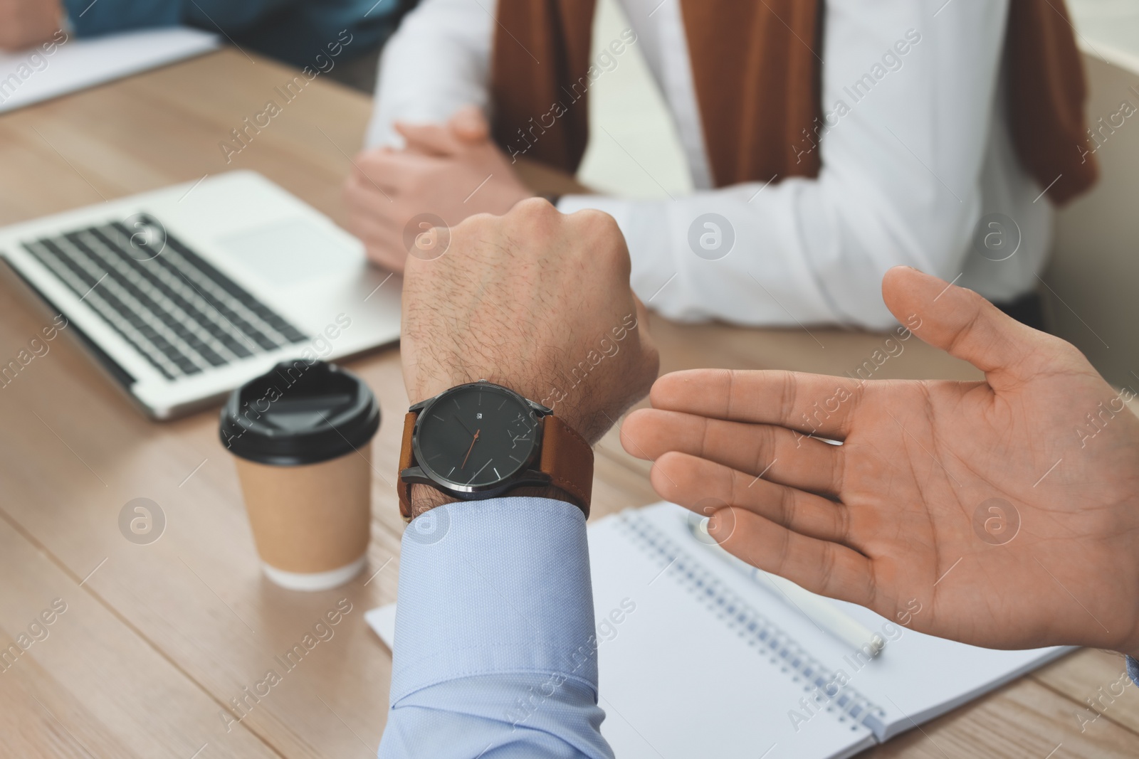 Photo of Businessman pointing on wrist watch while scolding employee for being late in office, closeup