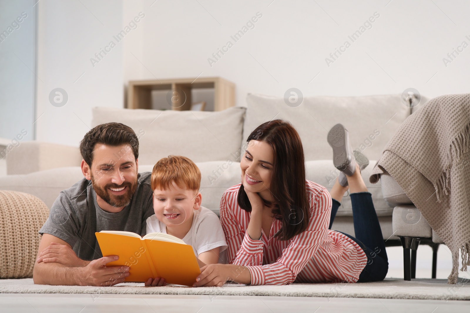 Photo of Happy parents with their child reading book on floor at home